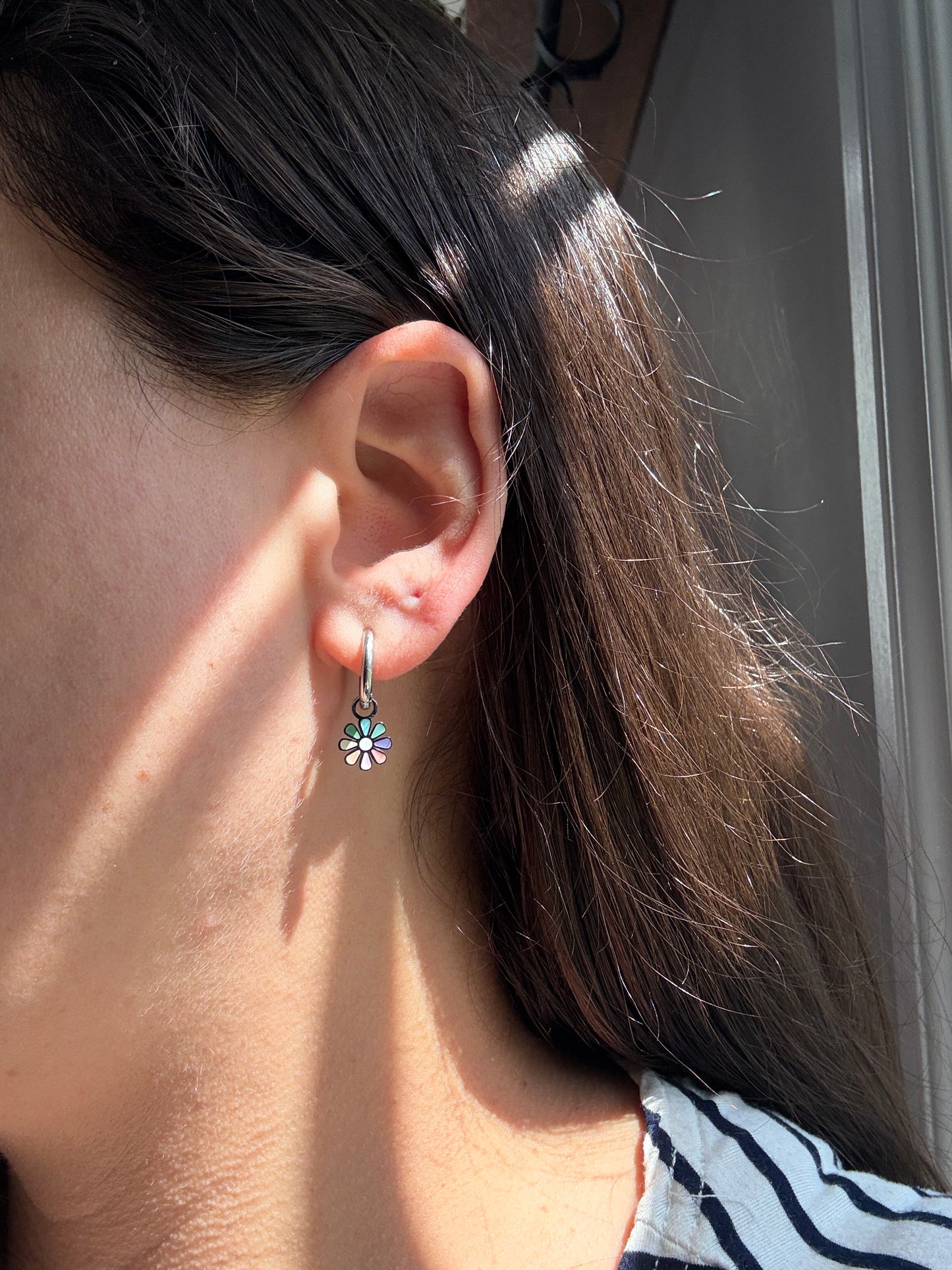 Close-up of an ear with a floral earring, hair partially covering the face.