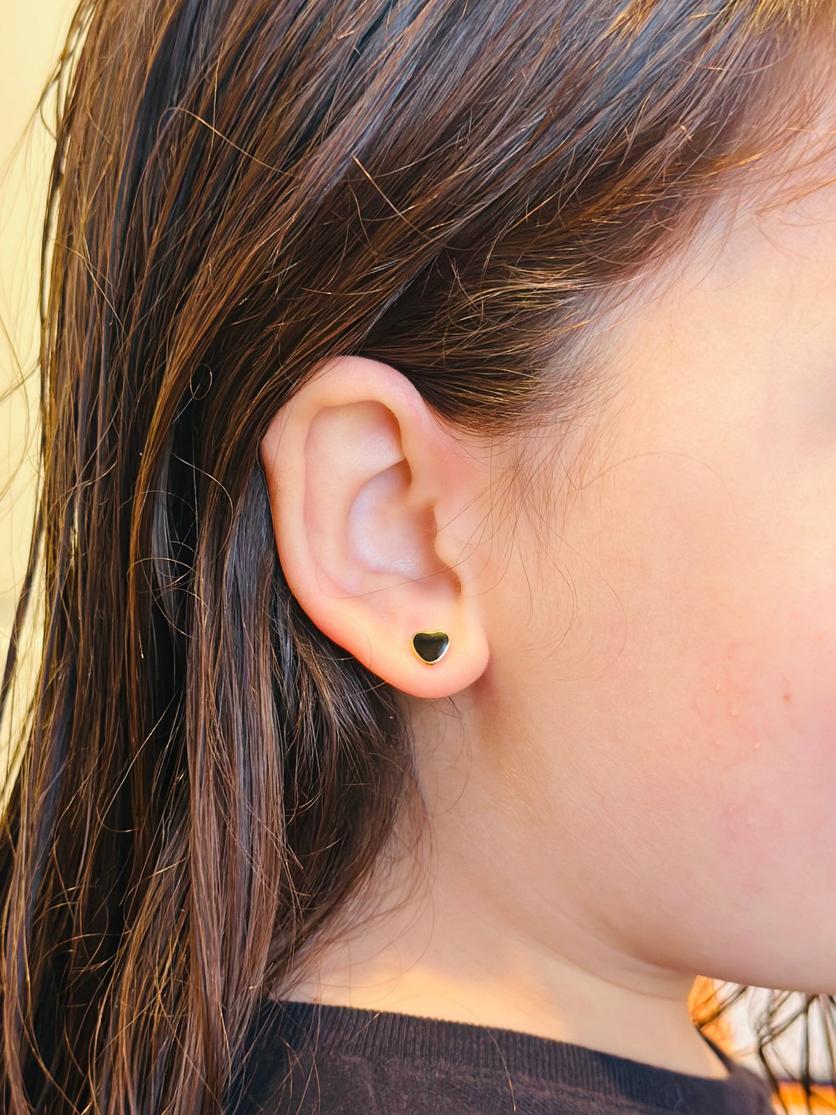 Black and Gold Heart Studs Shown being worn on a kids ear 