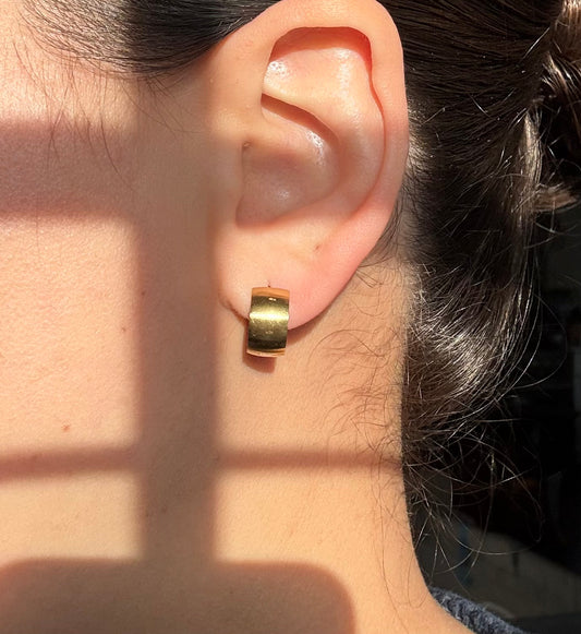 Gold Chunky Huggie Hoops worn on an ear