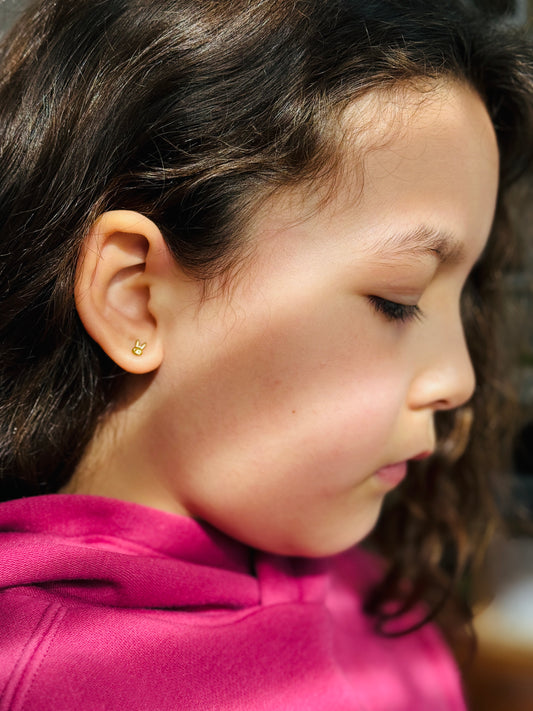 Gold Tiny Bunny Studs shown worn on a girl’s ear