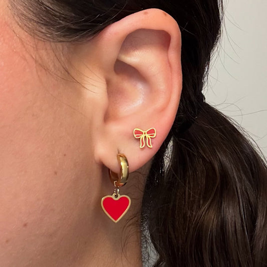 Red and gold studs stacked with a red and gold heart dangle Huggie hoop. Both worn on an ear to show size.