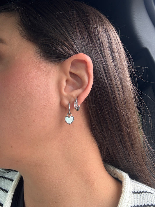 Close-up of an ear with silver earrings against a blurred background