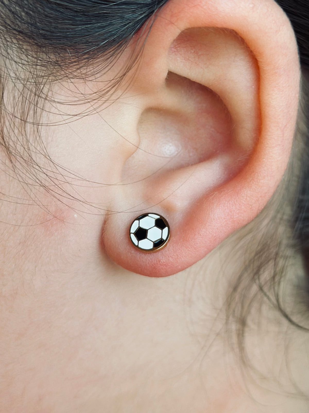 Soccer ball studs shown being worn on a kids ear