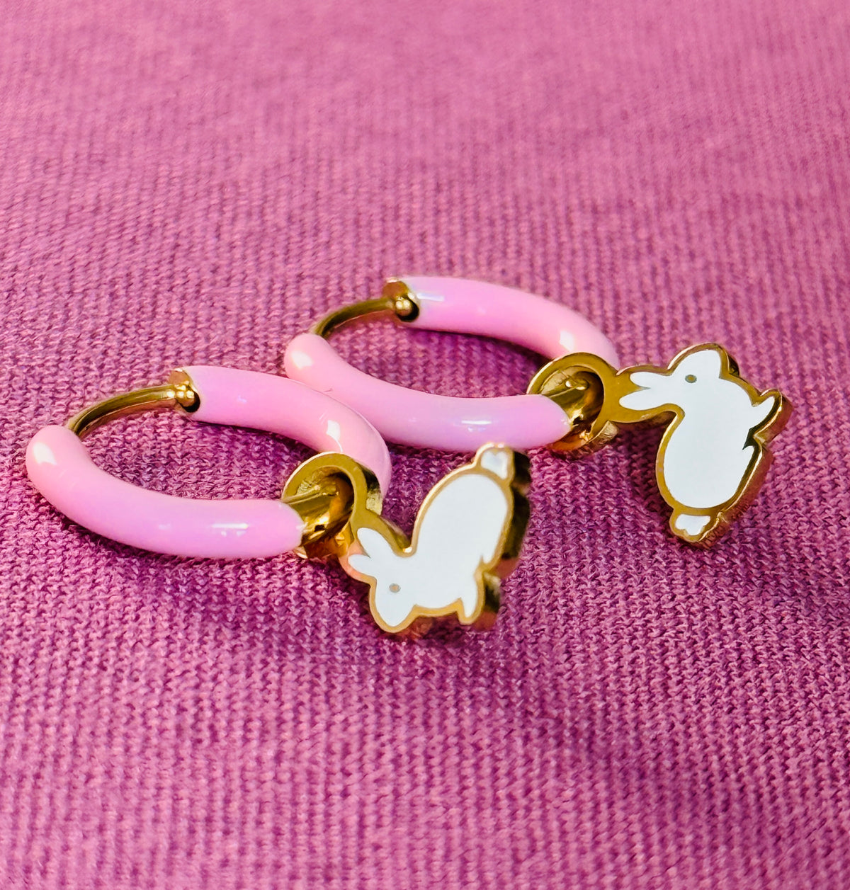 Pink hoop earrings with gold accents and white chicken charms on a pink background