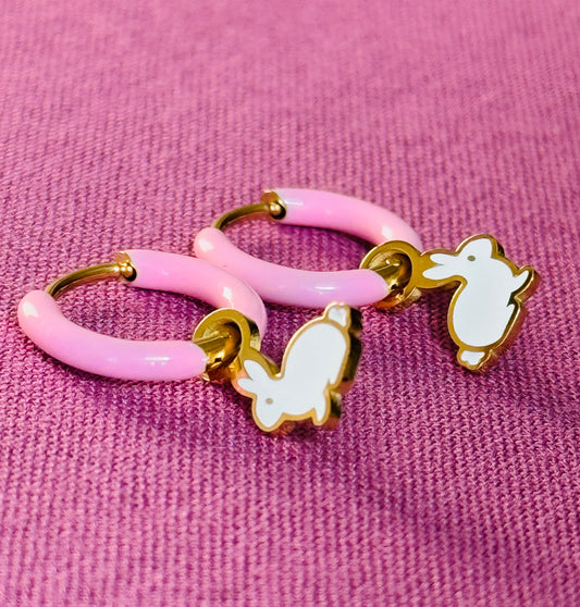 Pink hoop earrings with gold accents and white chicken charms on a pink background