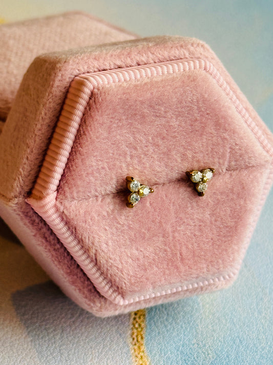 Pair of gold earrings with crystals in a pink jewelry box on a  pastel color background