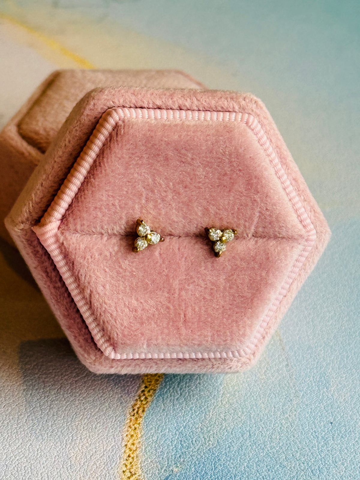 Pair of earrings in a pink hexagonal jewelry box on a soft background